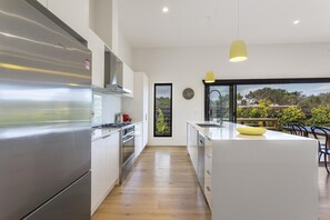 Een moderne keuken met roestvrijstalen apparatuur, een centraal eiland en uitzicht op de omgeving.