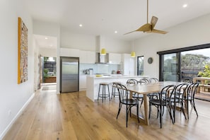 A modern kitchen with white cabinets, a central island, and a dining area with black chairs.