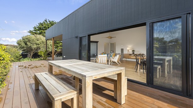 A modern house with a wooden deck and a dining area. - Yaringa, St Andrews Beach - Pristine new family living and only moments from the surf beach (ST ANDREWS BEACH)