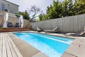 A backyard with a swimming pool, wooden deck, and lounge chairs. - Sorrento Beach House. (SORRENTO)