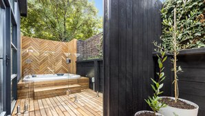 A modern outdoor hot tub area with wooden decking and a herringbone-patterned wall. - The Love Shack, Blairgowrie - Romantic, private bungalow, walk to Blairgowrie village and beach (BLAIRGOWRIE)