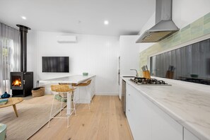 Une cuisine moderne dotée d’une cuisinière intégrée, d’une grande fenêtre et d’un téléviseur à écran plat fixé au mur.