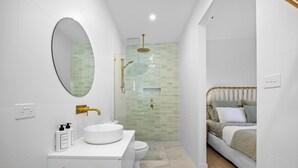 A modern bathroom with a white sink, gold fixtures, and a glass-enclosed shower. - The Love Shack, Blairgowrie - Romantic, private bungalow, walk to Blairgowrie village and beach (BLAIRGOWRIE)