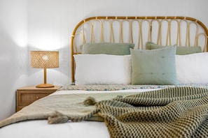 Un letto con una testiera in legno, una lampada da comodino e una coperta a motivi decorativi.