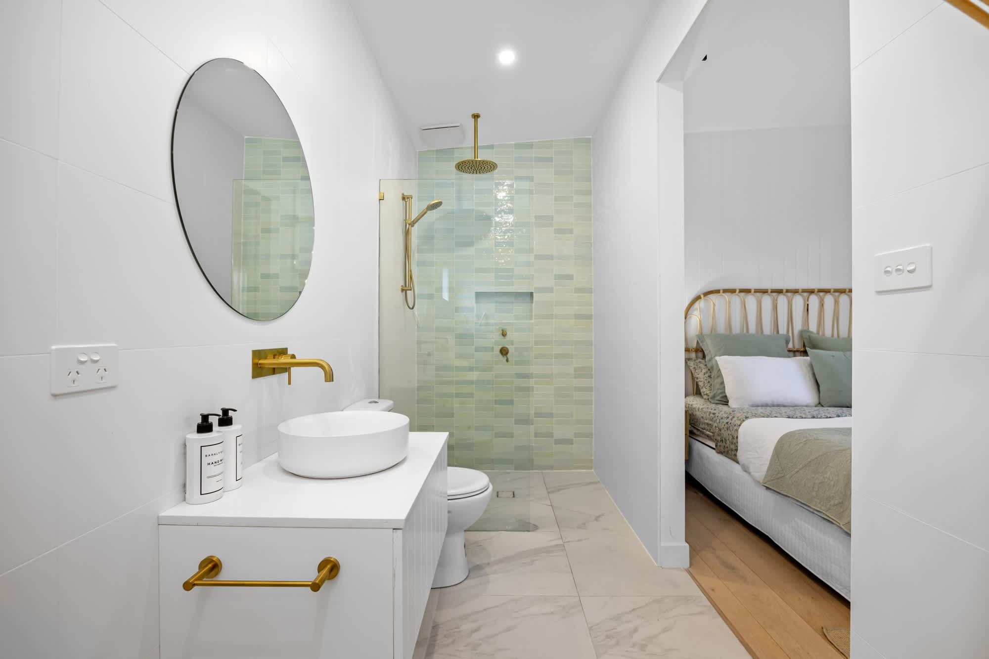 A modern bathroom with a white sink, gold fixtures, and a glass-enclosed shower.