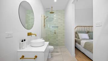 A modern bathroom with a white sink, gold fixtures, and a glass-enclosed shower.