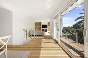 A modern interior with a wooden floor, a staircase, a sofa, and a TV.