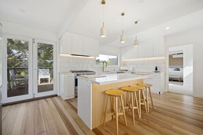 A modern kitchen with a central island, bar stools, and pendant lighting.
