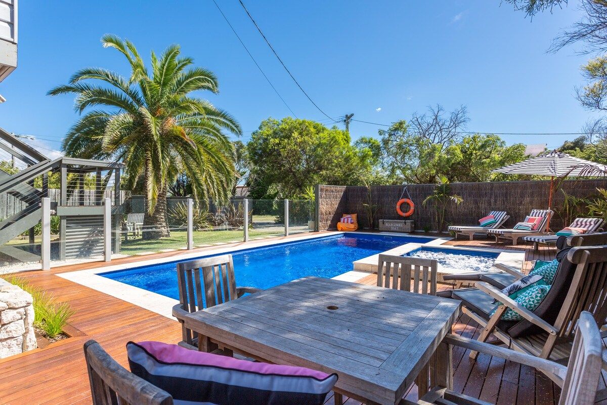 Ein Garten mit Schwimmbad, Liegestühlen und einer Holzterrasse.