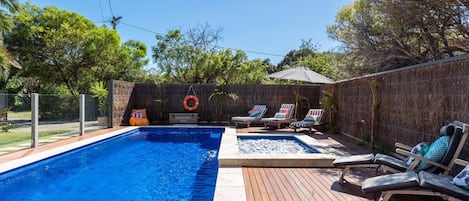 Une piscine avec des chaises longues et une bouée de sauvetage sur une terrasse en bois.