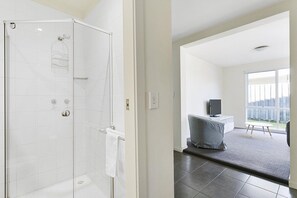 Une salle de bain moderne avec une douche à parois de verre, une serviette blanche et des toilettes bien visibles.