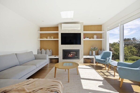 A modern living room with a fireplace, a sofa, a coffee table, and a TV mounted on the wall.