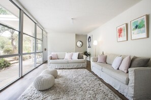 Una sala de estar moderna con dos sofás, un espejo redondo y obras de arte en la pared.