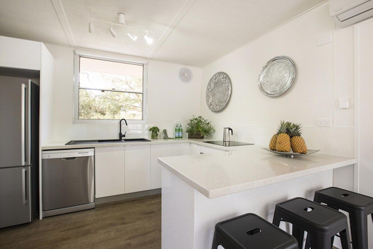 A modern kitchen with stainless steel appliances, a large island, and bar stools.