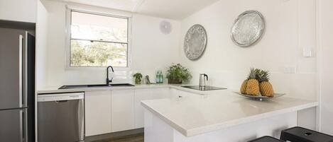 A modern kitchen with stainless steel appliances, a large island, and bar stools.