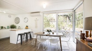 A modern kitchen with a central island, bar stools, and a dining area with a table and chairs.