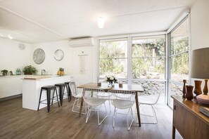 A modern kitchen with a central island, bar stools, and a dining area with a table and chairs.