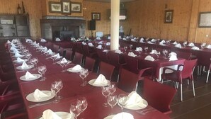 A banquet hall with long tables set for a formal event, featuring a fireplace and framed pictures on the walls.