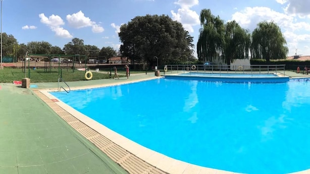 A rectangular swimming pool with a green deck and a lifeguard stand.