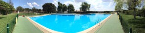A rectangular swimming pool with a green deck and a lifeguard stand. - Bungalows Camping Monfragüe (Malpartida de Plasencia)