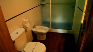A small bathroom with a toilet, bidet, and shower stall.