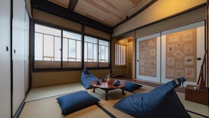Une pièce de style japonais traditionnel, avec un sol recouvert de tatamis, une petite table en bois et des coussins bleus.