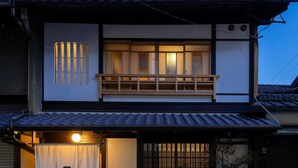 Une maison traditionnelle japonaise dotée d’un balcon en bois, de portes coulissantes et d’un toit recouvert de tuiles.