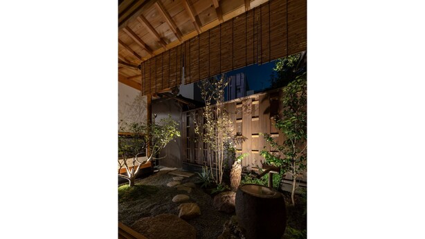 Un jardin japonais traditionnel, agrémenté d’une structure en bois, de sentiers en pierre et de diverses plantes.
