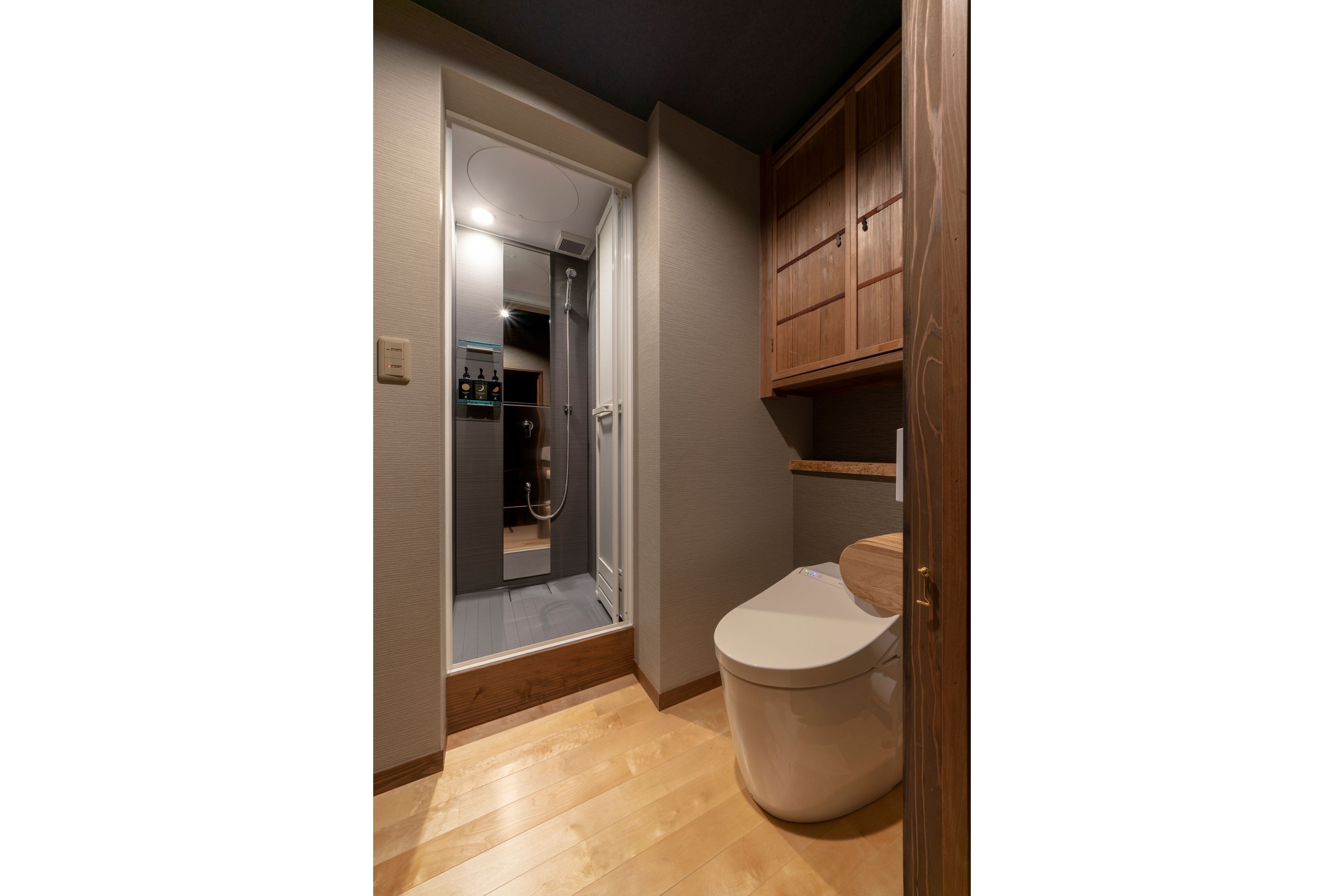 Un baño con tocador de madera, inodoro y zona de ducha.