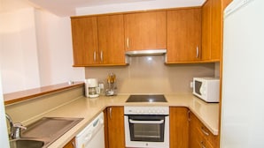 A compact kitchen with wooden cabinets, a built-in oven, a microwave, and a dishwasher.