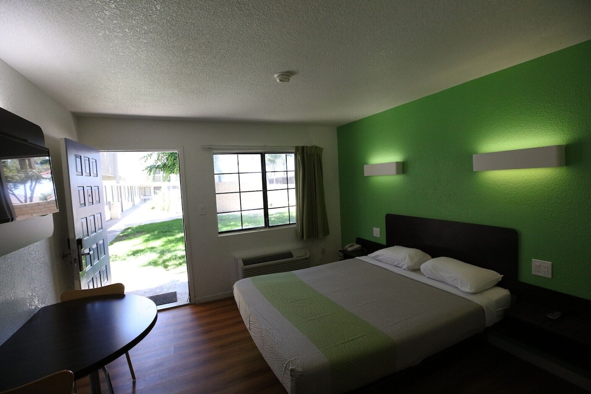 Habitación de hotel con cama, escritorio, silla, ventana y puerta.