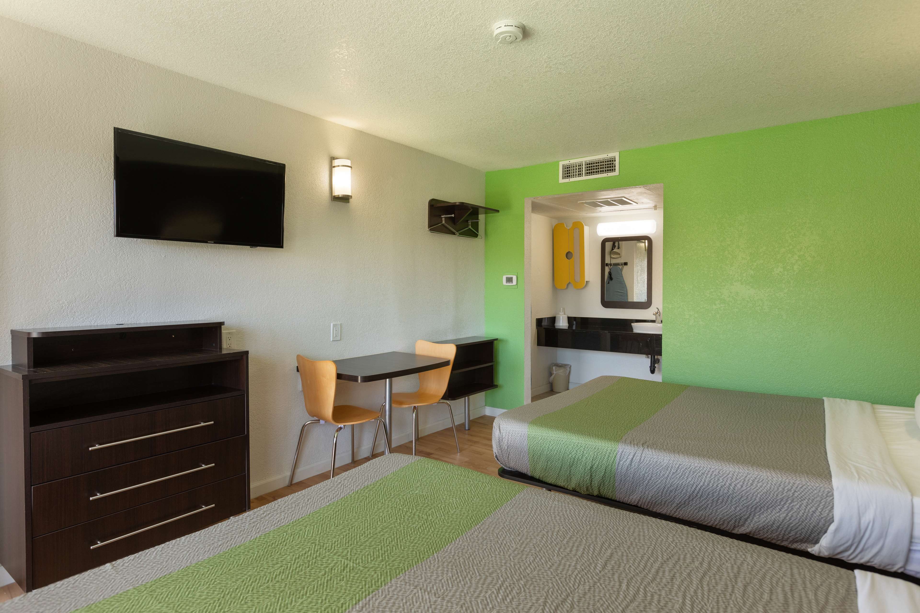 Una habitación de hotel con cama, escritorio, silla, cómoda y televisión.