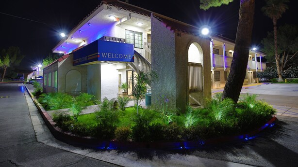 A hotel with a 'WELCOME' sign, a well-lit entrance, and a landscaped garden area. - Studio 6 Barstow, CA (Barstow)