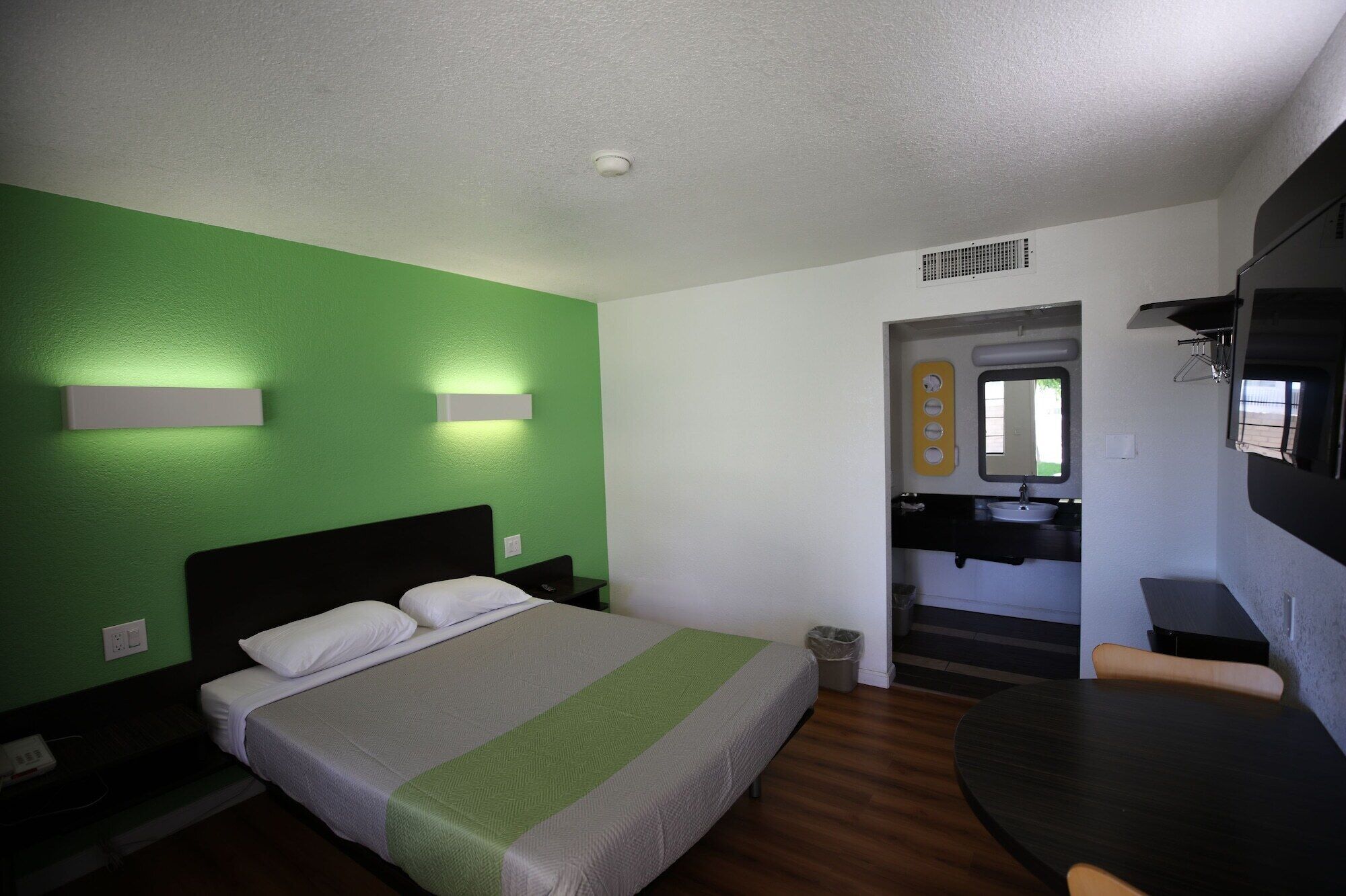 A hotel room with a bed, a desk, and a bathroom visible through an open door.