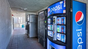 A vending machine with a Pepsi logo, surrounded by a tiled floor and a metal fence. - Studio 6 Barstow, CA (Barstow)