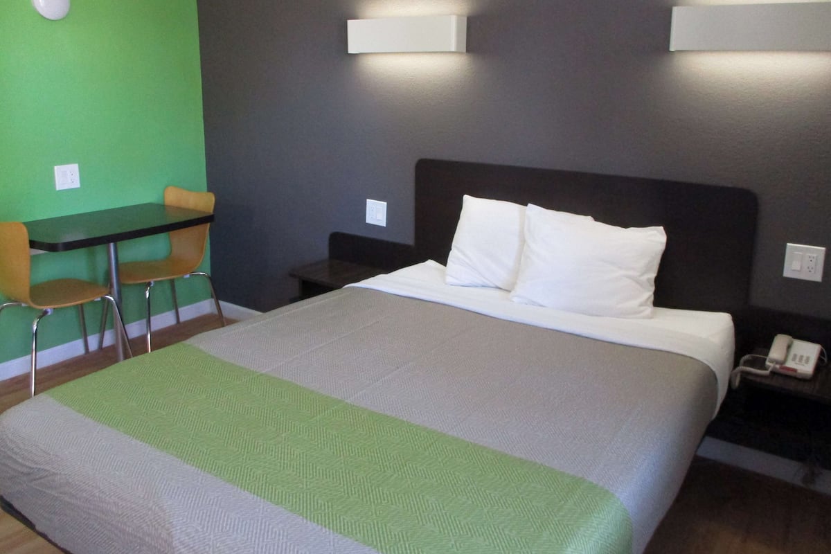 Una habitación de hotel con una cama, un escritorio y sillas, y una pared verde.