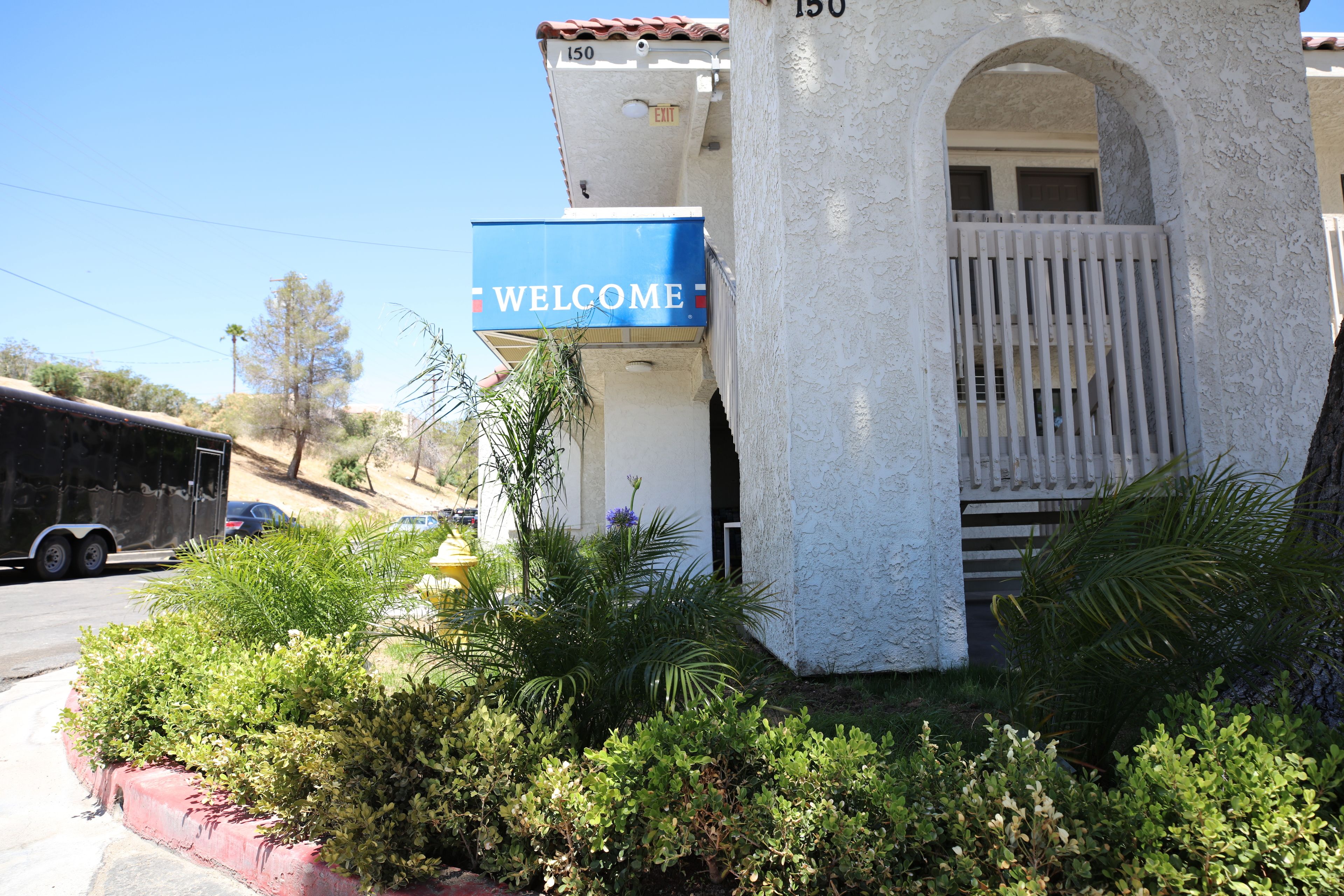 Un edificio con un letrero que dice 'WELCOME', una entrada con portones y una borda roja.
