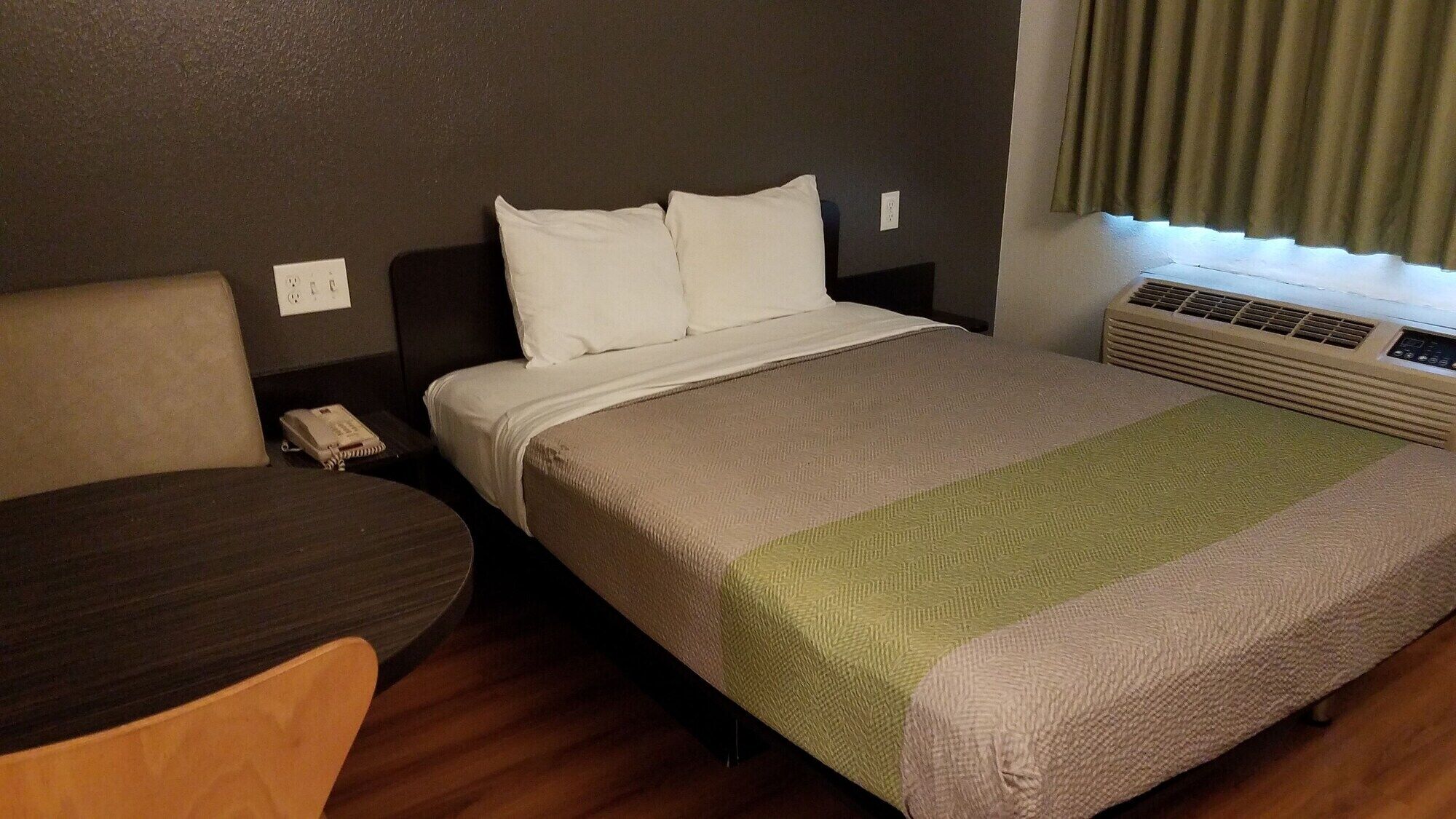 A hotel room with a bed, a desk, and a chair.