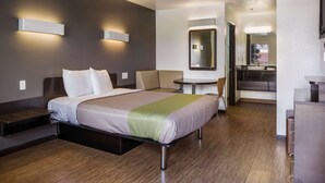 Ett modernt hotellrum med en säng, sängbord, ett litet skrivbord och en stol.