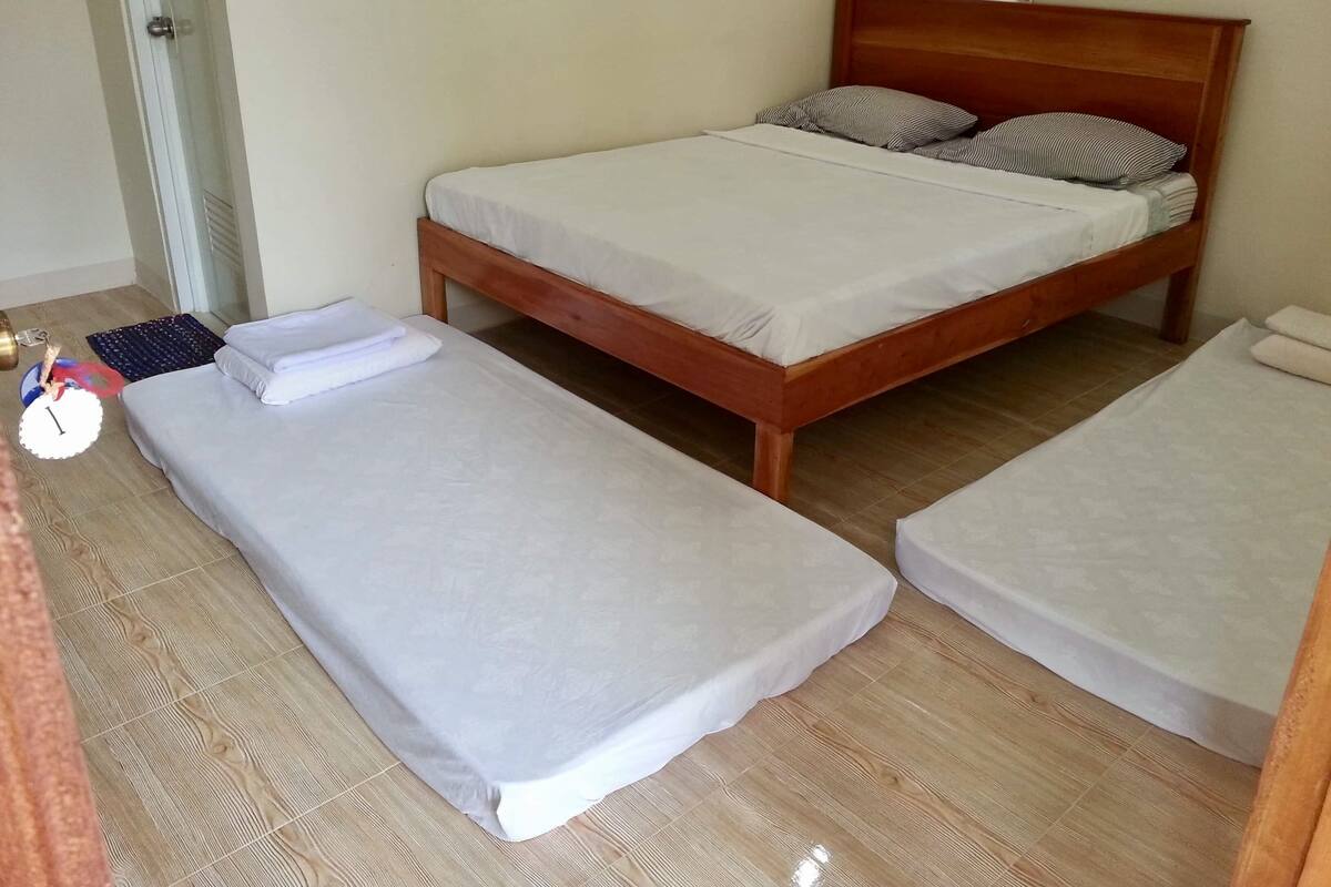 Une chambre avec un lit simple et deux lits individuels.