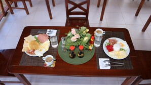 A dining table with breakfast plates, condiments, and a decorative centerpiece. - D's Ocean View Beach Resort (Siquijor)