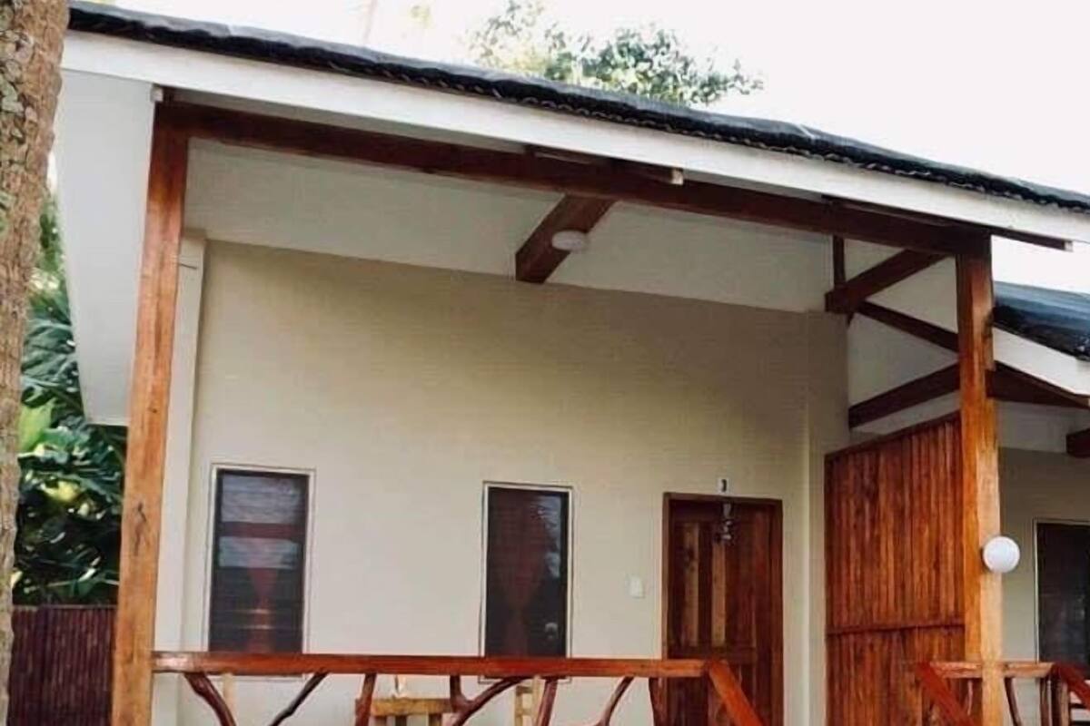 Une maison dotée d’un porche couvert, d’une balustrade en bois et d’un escalier menant à l’entrée.