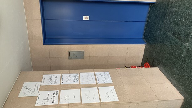 A room with a blue cabinet, a tiled floor, and several handwritten notes on the floor. - Yamanami'Tel - Hostel (Kumamoto)