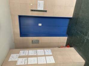 A room with a blue cabinet, a tiled floor, and several handwritten notes on the floor.