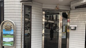 A building entrance with a glass door, a keypad lock, and a sign instructing to return the key. - Yamanami'Tel - Hostel (Kumamoto)