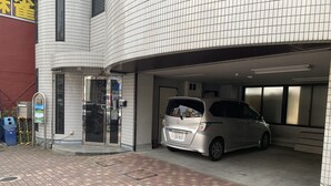 A parking garage entrance with a silver minivan parked inside. - Yamanami'Tel - Hostel (Kumamoto)