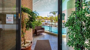 Zona de piscina interior amb pared de maó, una banca i plantes en testos.