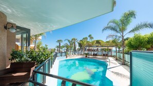Zona de piscina amb una piscina blava cristal·lina, gandules i palmeres.
