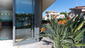 Un edifici modern amb entrada de vidre, zona de piscina i vistes als edificis veïnals.