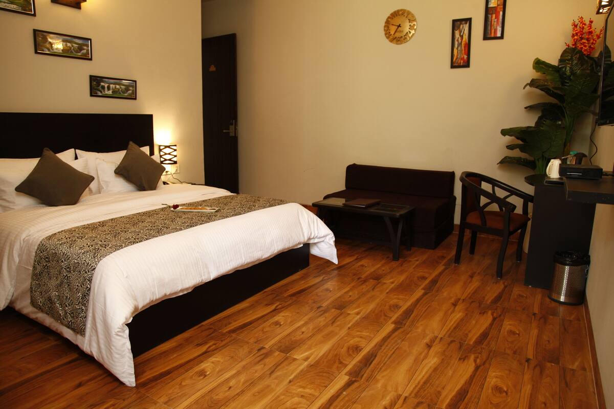 Quarto de hotel com uma cama grande, uma secretária pequena e uma cadeira.